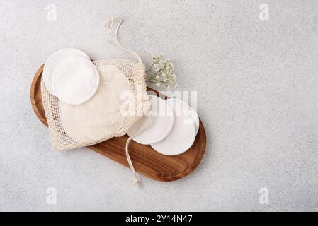 Flach liegend mit umweltfreundlichen Pflegeprodukten, einschließlich wiederverwendbarer Wattepads in einer Kordelzugtasche und einem Holztablett. Perfekt für nachhaltige Schönheit Stockfoto