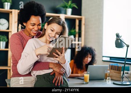 Glückliche alleinerziehende Mutter hilft bei der Online-Schule für multiethnische Kinder zu Hause. Stockfoto