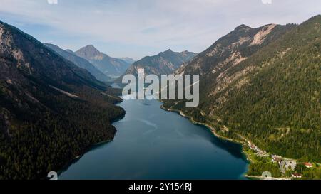 Eingebettet zwischen majestätischen Bergen spiegelt ein ruhiger See die umliegenden Gipfel in Plansee, Österreich, wider. Die lebhaften Grün- und Blautöne harmonieren und laden Naturliebhaber zum Entspannen und Entspannen ein. Stockfoto