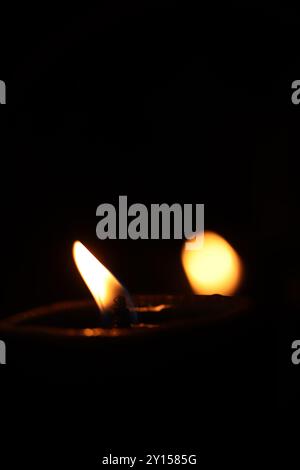 Nahaufnahme des Lichts einer brennenden Kerze an Schwarzer Hintergrund Stockfoto
