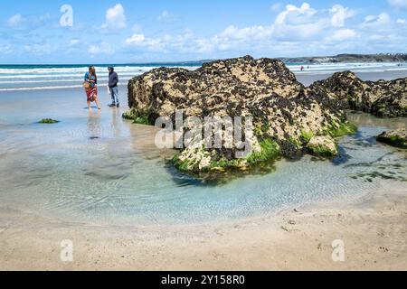 Besucher, die bei Ebbe am Towan Beach in Newquay in Cornwall in Großbritannien spazieren gehen. Stockfoto