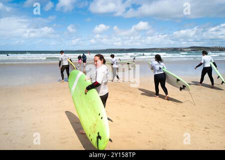 Eine Gruppe von Surf-Neulingen, die eine Surfstunde in der SSS Surfschule am Towan Beach in Newquay in Cornwall in Großbritannien absolvieren. Stockfoto