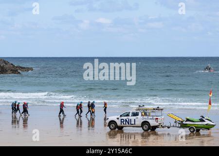 Coasteering Instruktoren führen eine große Gruppe von Menschen auf eine Küstenfahrt entlang des Towan Beach vorbei an einem RNLI Royal National Lifeboat Institutio Stockfoto