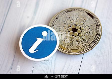 KIEW, UKRAINE - 17. AUGUST 2024 Cardano ADA Münze und Informationsschild auf hölzernem Hintergrund Nahaufnahme Stockfoto