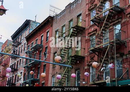 New York, USA - 05. September 2024: Blick auf die Straße in Chinatown mit Backsteinhäusern und externen Feuerlöschflüchten mit hängendem sphärischem lan Stockfoto