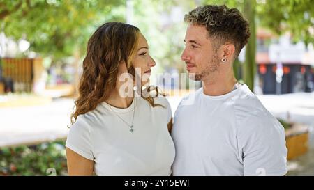 Ein liebevolles Paar schaut sich in einem grünen Park in die Augen und vermittelt ein Gefühl von Romantik und Gesellschaft im Freien. Stockfoto