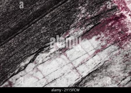 Nahtstruktur aus natürlichem Granit mit einer Mischung aus schwarzen, weißen und rötlich-violetten Tönen, mit organischen, fließenden Mustern. Stockfoto