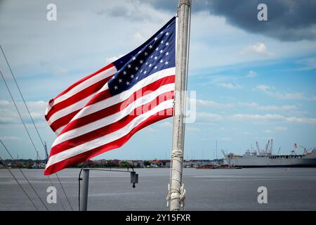 Der Wind weht eine amerikanische Flagge auf dem Heck der USS Wisconsin (BB-64) in der Innenstadt von Norfolk, Virginia. Stockfoto