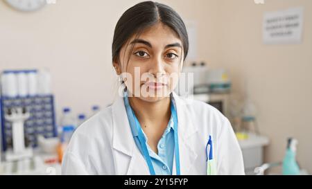 Eine südasiatische Ärztin posiert in einem Laborumfeld und strahlt Vertrauen und Fachwissen aus. Stockfoto