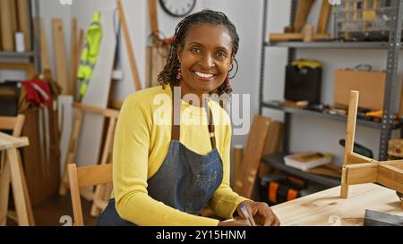 Lächelnde afroamerikanerin mit Schürze in einer Tischlerei Stockfoto