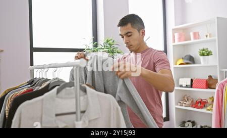 Hispanischer Mann, der in einem hellen, modernen Ankleidezimmer Kleidung auswählt Stockfoto