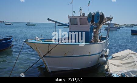 Traditionelles Fischerboot in einem ruhigen Hafen von porto cesareo, italien, mit klarem blauem Wasser unter hellem Himmel, das den Charme von apulien zum Ausdruck bringt Stockfoto