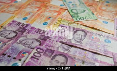 Philippinische Banknoten in verschiedenen Stückelungen sind verteilt und zeigen farbenfrohe Pesos-Währungen der philippinen. Stockfoto