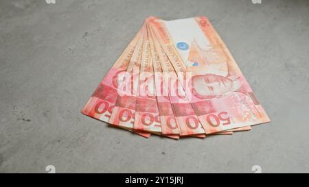 Philippinische Peso-Banknoten, die ordentlich auf einer Betonoberfläche angeordnet sind und farbenfrohe Geldscheine in flacher Lage darstellen. Stockfoto