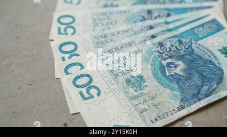 Polnische Zloty-Banknoten, die auf einer Betonoberfläche verteilt sind, zeigen detaillierte Designelemente und die narodowy Bank polski-Inschrift. Stockfoto