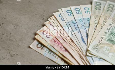 Polnische Zloty-Banknoten auf einer Betonoberfläche, die die verschiedenen Stückelungen zeigen und das unverwechselbare Design der Währung betonen. Stockfoto