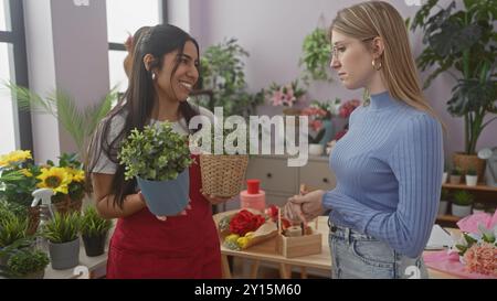 Zwei Frauen, die in einem Blumengeschäft tätig sind, wobei eine Pflanzen anbietet und die andere sie untersucht. Stockfoto