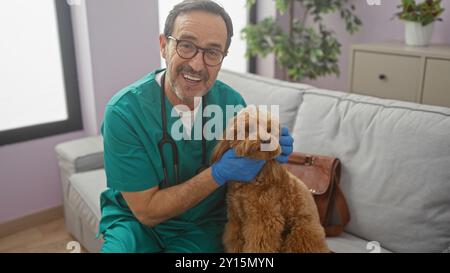 Ein lächelnder hispanischer Mann mittleren Alters hält einen Pudel im Inneren Stockfoto