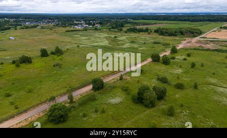 Blick aus der Vogelperspektive auf ein Wohngebiet mit modernen Häusern, umgeben von grünen Feldern und Bäumen. Die Landschaft bietet eine Mischung aus entwickeltem und natürlichem Raum Stockfoto