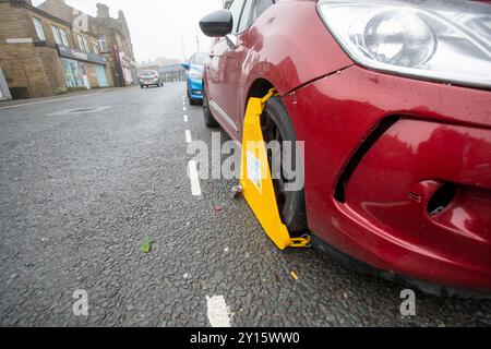 Ein Auto, das wegen Nichtentrichtung der Kfz-Verbrauchsteuer in Großbritannien an der High Street in Queensbury, West Yorkshire, Großbritannien, eingeklemmt wurde. Quelle: Windmill Images/Alamy Live News Stockfoto