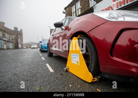 Ein Auto, das wegen Nichtentrichtung der Kfz-Verbrauchsteuer in Großbritannien an der High Street in Queensbury, West Yorkshire, Großbritannien, eingeklemmt wurde. Quelle: Windmill Images/Alamy Live News Stockfoto