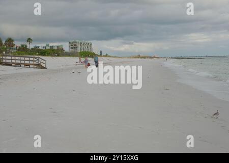 Weiter Blick nach Süden auf Sunset Beach in Treasure Island Florida über den Strand. Älteres Paar auf der linken Seite und Holzbrücke zum Strand. Führende Linien Stockfoto