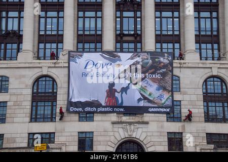 London, Großbritannien. September 2024. Greenpeace-Aktivisten entfalten ein massives Banner auf dem Unilever-Hauptquartier. Aktivisten blockierten auch die Eingänge zum Gebäude und sperrten sich in riesige Nachbildungen von Dove Deodorant Sticks ein, um gegen die Plastikverschmutzung durch Dove Produkte zu protestieren. Quelle: Vuk Valcic/Alamy Live News Stockfoto