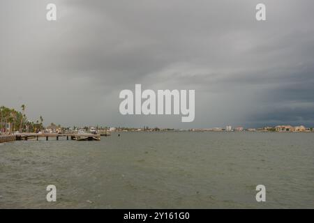 Weite Aussicht über Bay Water in Richtung Vina Del Mar Island an einem bewölkten Tag am späten Nachmittag. Bootsanlegestelle und Boote auf der linken Seite. Dunkle Sturmwolken Stockfoto