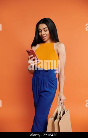 Eine modische Frau überprüft gerne ihr Handy, während sie Einkaufstaschen hält. Stockfoto