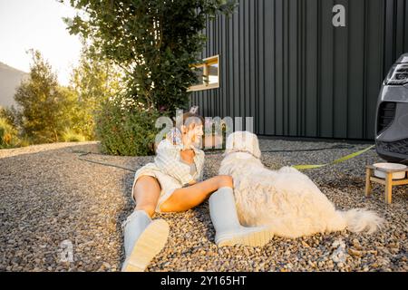 Ein ruhiger Moment der Entspannung zwischen einer Frau und ihrem großen Hund und genießen Sie das Morgensonnenlicht in einer friedlichen Gartenumgebung. Dieses Bild erfasst die e Stockfoto