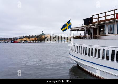 Stockholm, Schweden. 15. April 2024: Die weiße Fähre legt mit schwedischer Flagge im Hafen an Stockfoto