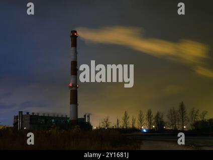 Blick auf den Heizraum mit einem hohen Kamin und Rauch mitten in der Nacht Stockfoto