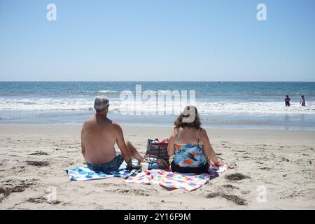 Los Angeles, USA. September 2024. Menschen sitzen am Santa Monica Beach in Los Angeles, Kalifornien, USA, 4. September 2024. Am Ende des Sommers stehen Städte im Westen der Vereinigten Staaten immer noch unter beispiellosen Hitzewellen, die seit langem bestehende Temperaturrekorde zerstört und Gemeinden an ihre Grenzen getrieben haben. Quelle: Zeng Hui/Xinhua/Alamy Live News Stockfoto