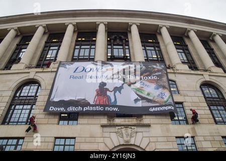 London, England, Großbritannien. September 2024. Greenpeace-Aktivisten skalieren das Unilever-Hauptquartier und entfalten ein massives Banner, das die Firma auffordert, Plastik abzugeben. Aktivisten blockierten auch die Eingänge zum Gebäude und sperrten sich in riesige Nachbildungen von Dove Deodorant Sticks ein, um gegen die Plastikverschmutzung durch Dove Produkte zu protestieren. (Kreditbild: © Vuk Valcic/ZUMA Press Wire) NUR REDAKTIONELLE VERWENDUNG! Nicht für kommerzielle ZWECKE! Quelle: ZUMA Press, Inc./Alamy Live News Stockfoto