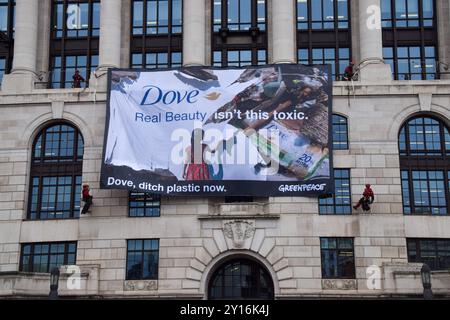 London, England, Großbritannien. September 2024. Greenpeace-Aktivisten skalieren das Unilever-Hauptquartier und entfalten ein massives Banner, das die Firma auffordert, Plastik abzugeben. Aktivisten blockierten auch die Eingänge zum Gebäude und sperrten sich in riesige Nachbildungen von Dove Deodorant Sticks ein, um gegen die Plastikverschmutzung durch Dove Produkte zu protestieren. (Kreditbild: © Vuk Valcic/ZUMA Press Wire) NUR REDAKTIONELLE VERWENDUNG! Nicht für kommerzielle ZWECKE! Quelle: ZUMA Press, Inc./Alamy Live News Stockfoto