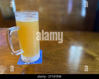 Helles Bernsteinbier in Glasbecher mit Griff in Bar- oder Restaurant-Umgebung Stockfoto