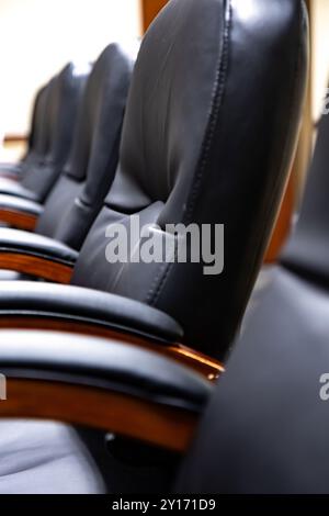 Reihe schwarzer Ledersessel, die sich am Executive Meeting Table im modernen Konferenzraum befinden Stockfoto