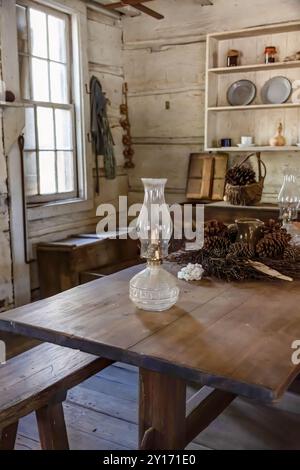 Nahaufnahme der antiken Öllampe auf dem Bauernhof-Tisch in Blockhütte der 1800er Jahre mit historisch akkurater Küche Stockfoto