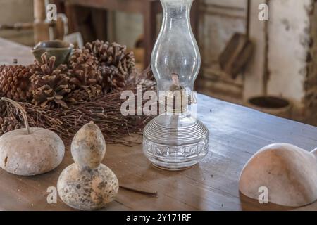 Nahaufnahme der antiken Öllampe auf dem Bauernhof-Tisch in Blockhütte der 1800er Jahre mit historisch akkurater Küche Stockfoto