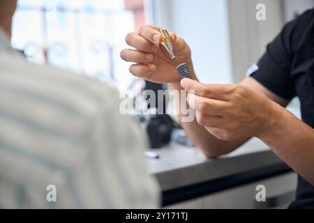 Zahnarzt zeigt dem Patienten ein Modell eines Zahnimplantats Stockfoto