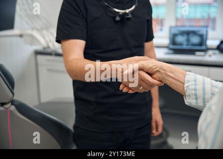 Der Arzt begrüßt die ältere Dame an der Rezeption mit Handschlag Stockfoto