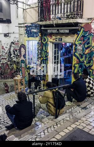 Menschen beobachten in Lissabon, Straßenfotografie - lauschen einem Café-Busker auf den Stufen den Burgberg hinauf. Stockfoto