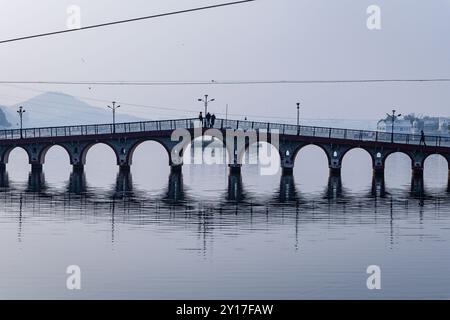 Ein ruhiger Vormittag an Udaipur's historischer Bogenbrücke über dem ruhigen Wasser des Sees wird in udaipur rajasthan india aufgenommen. Stockfoto