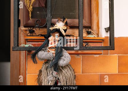 Hexenpuppe für Halloween-Dekorationen im Fenster des Hauses Stockfoto