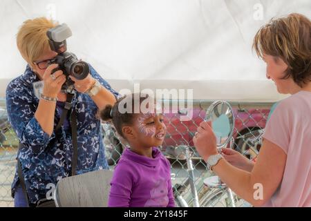 Beek, South Limburg, Niederlande. September 2014. Brünette Mädchen mit professionell bemalten Fantasy Gesicht, Erwachsene Frau zeigt Ergebnis im Spiegel und Stockfoto