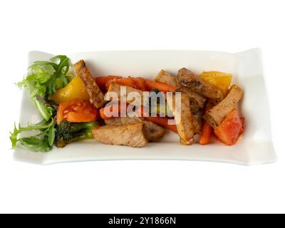 Köstliches gebratenes Gemüse und Schweinefleisch auf eleganter weißer Platte. Stockfoto