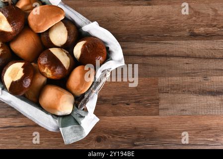 Große Auswahl an verschiedenen Brötchen im Korb. Auf einem rustikalen Holztisch mit Kopierraum. Stockfoto