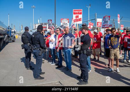 Detroit, Michigan, USA. September 2024. Die Polizei eskortiert einen Lkw durch die Streiklinie, während Mitglieder der Teamsters Union am zweiten Tag eines Streiks gegen die Raffinerie Marathon Petroleum sind. Die union arbeitet seit Januar ohne Vertrag. Die Hauptprobleme sind eine Lohnerhöhung, die der Inflation der letzten vier Jahre entspricht, und die Erhaltung der Leistungen. Marathon hat Ersatzarbeiter ins Leben gerufen, um die Raffinerie am Laufen zu halten. Quelle: Jim West/Alamy Live News Stockfoto