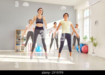 Gruppe fröhlich fitter junger Frauen, die während eines Workouts im Fitnessstudio Springübungen machen Stockfoto