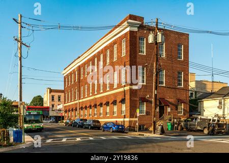 Nyack, NY - USA - 5. September 2024 seitliche Rückansicht des dreistöckigen historischen Nyack Business Centers aus rotem Backstein leuchtet bei Sonnenuntergang warm. Das Hotel befindet sich an der Hauptstraße Stockfoto